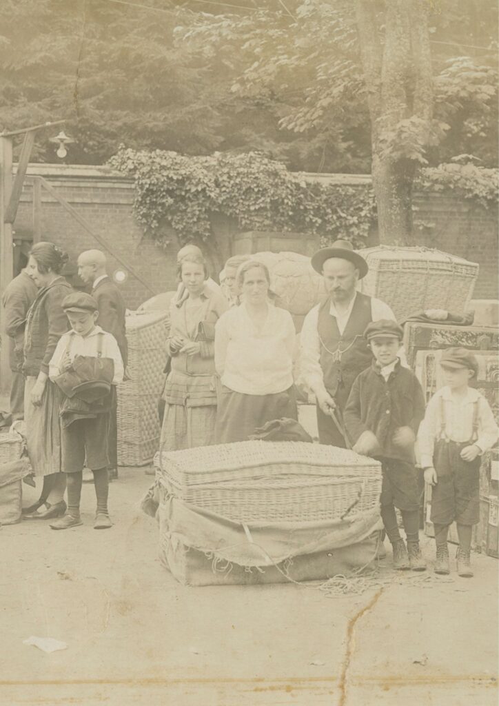 Czarno-białe zdjęcie ze zbiorów Muzeum Emigracji. Przedstawia grupę uchodzców w historycznych strojach